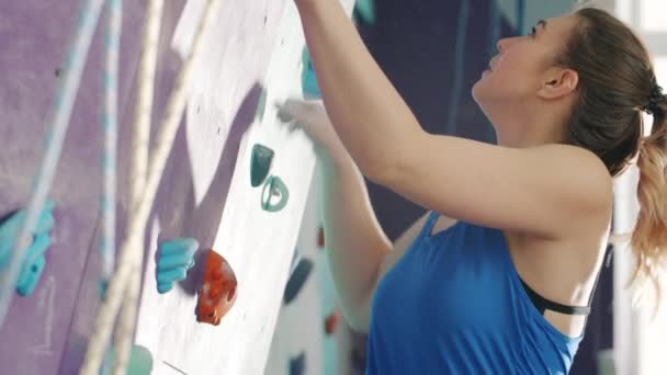 Mooie dame klimmen in sportcentrum genieten van rotsklimmen alleen binnen — Stockvideo