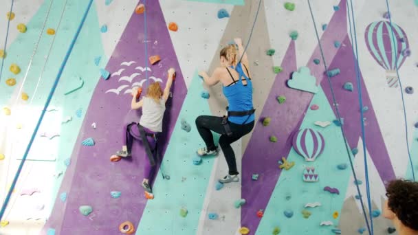 Vrouw en kind klimmen op kunstmatige muur doet high-five genieten van indoor sport — Stockvideo