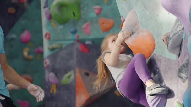 Actief kind klimmen op kunstmatige muur, terwijl vader ondersteuning van het waarborgen van veiligheid — Stockvideo