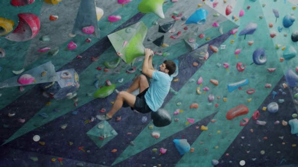 Yetenekli erkek tırmanışçı modern spor salonunda kayaları kavrıyor. — Stok video