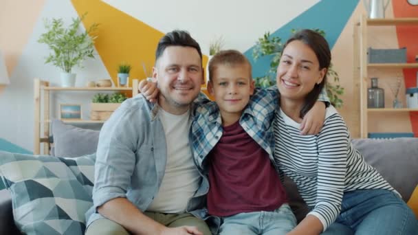 Porträt von Eltern und Kind lächelnd auf Sofa in modernem Studio-Appartement — Stockvideo