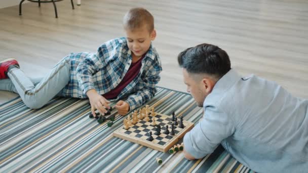 Pai amoroso jogando xadrez com criança inteligente ensinando criança jogo de tabuleiro inteligente — Vídeo de Stock