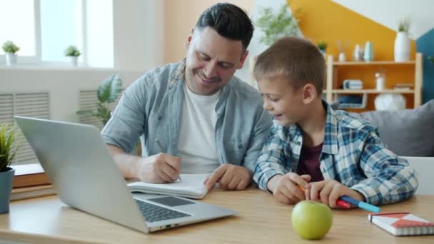 Mladý dospělý muž kreslení v notebooku baví s šťastným dítětem doma — Stock video