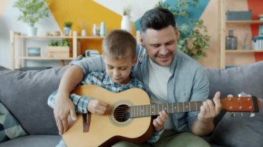 Mutlu aile babası ve oğlu evde gitar çalıp eğleniyorlar.