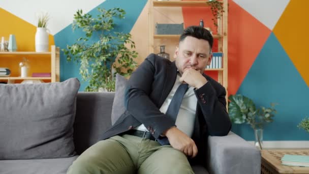 Besorgter Geschäftsmann in formeller Kleidung sitzt mit unglücklichem Gesicht auf Couch — Stockvideo