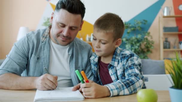 Cuidar padre creativo hombre dibujo cuadros mientras niño viendo sentado en escritorio en casa — Vídeo de stock