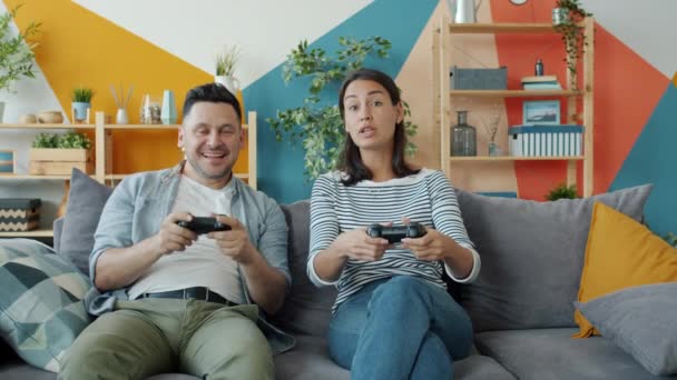 Bonito jovem casal namorado e namorada jogando videogame no sofá em casa . — Vídeo de Stock