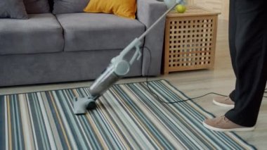 Yaşlı adamın evde temizlik yapması, halı süpürgesi ile süpürmesi.