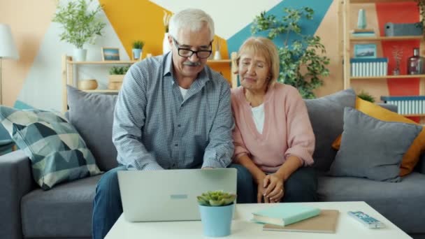 Alegre personas mayores que utilizan el ordenador portátil para hacer videollamadas haciendo gestos en el apartamento — Vídeos de Stock