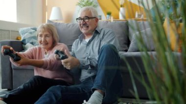 Oyun oynayan, video oyunu oynayan ve stüdyo dairede konuşan yaşlı insanların yavaş çekimleri.