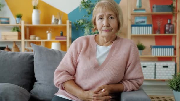 Portrait de vieille femme sérieuse avec coiffure moderne regardant la caméra dans la maison — Video