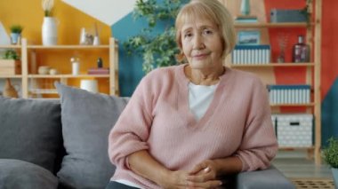 Evdeki kanepede oturmuş gülümseyen gündelik giysiler içinde güzel bir kadının portresi.