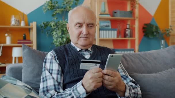 Senior man gör kontantlös betalning med bankkort och smartphone i huset — Stockvideo