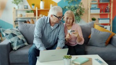 Yaşlı karı koca evde banka kartı ve dizüstü bilgisayarla para transferi yapıyorlar.