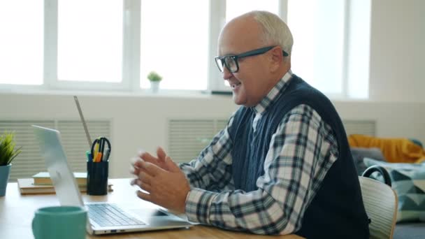 Feliz jubilado disfrutando de la comunicación en línea haciendo videollamada con portátil — Vídeos de Stock