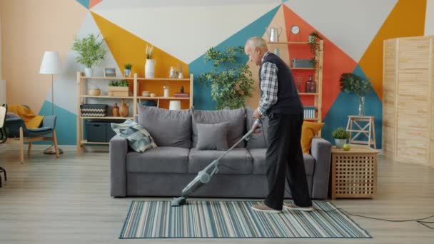 Senior muž vysávání koberec doma s vysavačem dělat domácí práce — Stock video