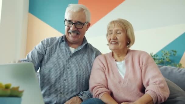 Boldog emberek házaspár élvezi az online video hívás laptop otthon — Stock videók