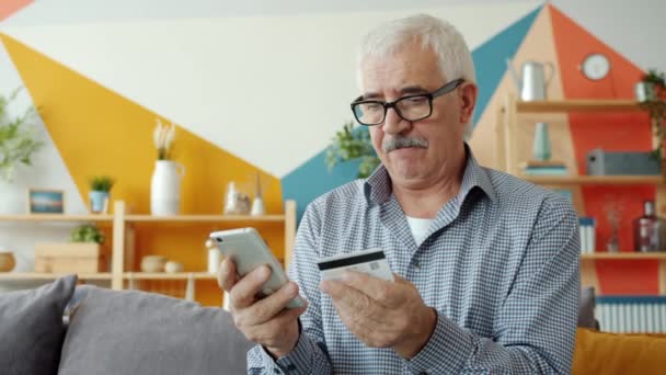 Медленное движение красивого взрослого мужчины, платящего онлайн банковской картой и смартфоном — стоковое видео