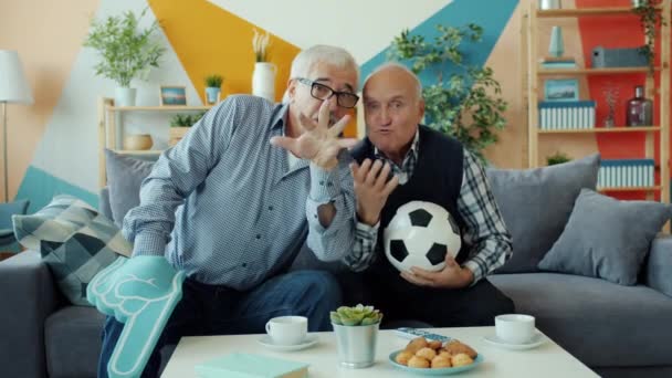 Old men cheering watching football match on TV doing high-five in apartment — Stock Video