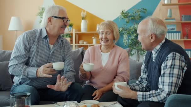 Gente jubilada amigos haciendo tostadas tazas de té y luego beber durante la fiesta en casa — Vídeo de stock