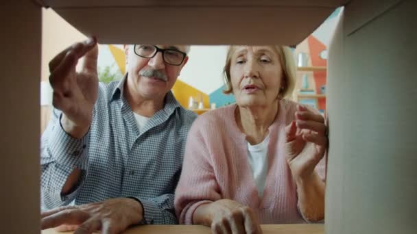 Langzame beweging van blij man en vrouw openen kartonnen doos en het nemen van vintage fles — Stockvideo