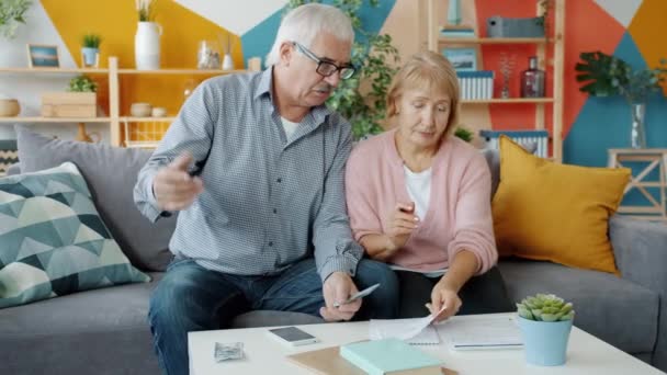 Movimento lento de marido e mulher aposentados olhando através de contas e contando dinheiro em casa — Vídeo de Stock