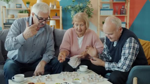 Gioioso anziani godendo lotto gioco al chiuso a casa a parlare divertente — Video Stock