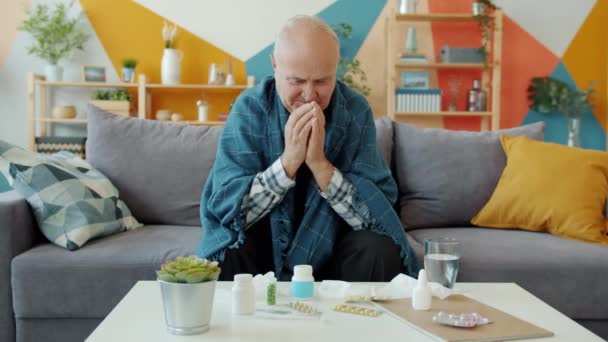 Uomo anziano malato coperto di tosse coperta guardando pillole acqua potabile — Video Stock