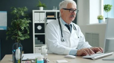 Klinikte bilgisayar daktiloyla çalışan üniformalı bir tıp uzmanı.