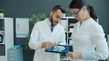 Erkek ve kadın sıhhiyeciler, ofiste çalışan röntgen görüntülerine bakıyorlar.