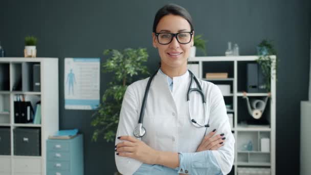 Retrato de menina sorridente em vestido branco médico de pé no escritório com os braços cruzados — Vídeo de Stock