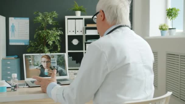 Az orvos tanácsot ad az egészségtelen személynek a kórházi számítógép használatával végzett internetes konzultáció során — Stock videók