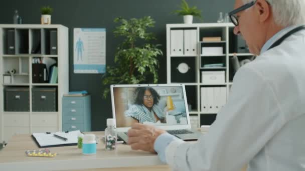 Médico falando com a menina afro-americana doente on-line usando o computador do escritório da clínica — Vídeo de Stock