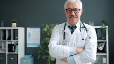 Dost canlısı gülümseyen doktor, klinikte tek başına durmuş, mutlu yüzüyle kameraya bakıyor.