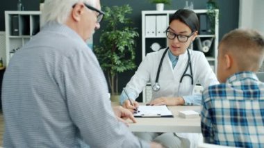 Doktor, aile büyükbabası ve torunuyla hastane ofisinde sağlığı tartışıyor.