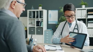 Doktor ve hasta tablet ekranına bakıyor. Hastanede MRI görüntülerini inceliyor.