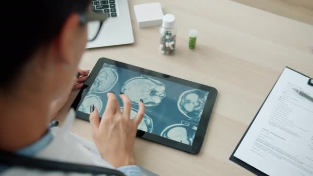 Young female doctor watching MRI images on tablet computer in clinic office — Stock Video