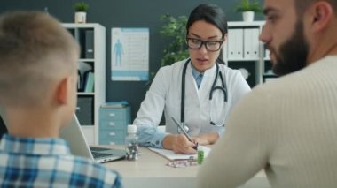 Pediyatrist dostu kadın hastane odasında genç bir adam ve çocukla konuşuyor.