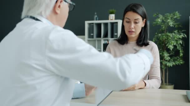 Paciente femenina que habla con el médico y firma la historia clínica durante la visita al hospital — Vídeo de stock