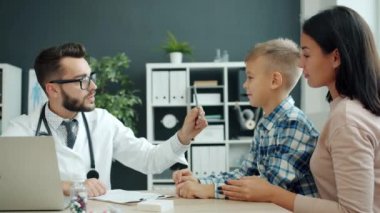 Erkek çocuk doktoru aile babası anne ve oğluyla konuşuyor. Çocuk dosyasını inceliyor.