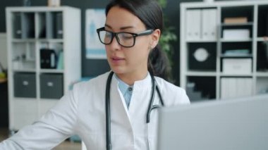 Hastanede bilgisayarla hastayla konuşan çekici genç bir kadın doktor.