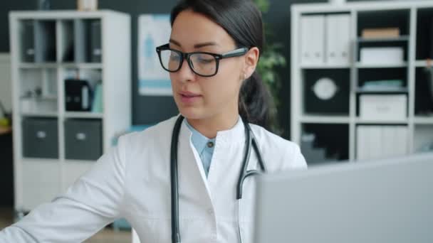 Hastanede bilgisayarla hastayla konuşan çekici genç bir kadın doktor. — Stok video