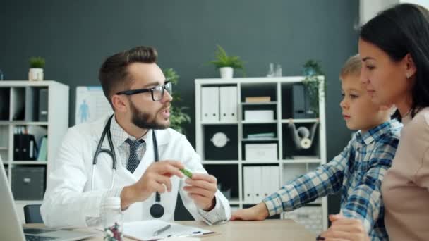 Médico discutiendo la medicación con la madre de la familia y el niño mostrando pastillas en el hospital — Vídeos de Stock