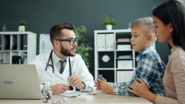 Anne gülerken çocuk hastanede dost canlısı çocuk doktoruyla konuşuyor.