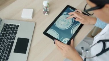 Klinikte çalışan MRI görüntülerini inceleyen tablet kullanan tıp uzmanı