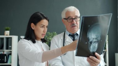 Kadın ve erkek doktorlar, klinikte çalışan kafatası röntgenini tartışıyorlar.