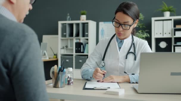 Kvinnlig läkare talar med äldre man patient på kontoret under tid på kliniken — Stockvideo