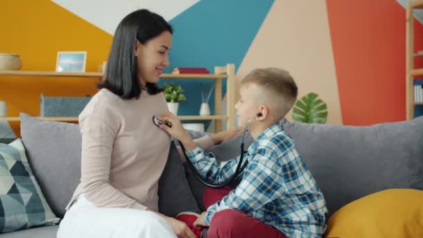 Roztomilé dítě hraje s matkou zkoumá se stetoskopem v domě baví společně — Stock video