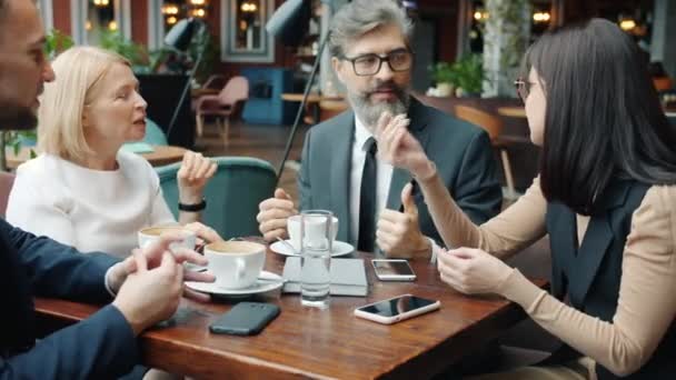 Бизнесмены и предпринимательницы выступают в кафе, обсуждая жесты работы — стоковое видео
