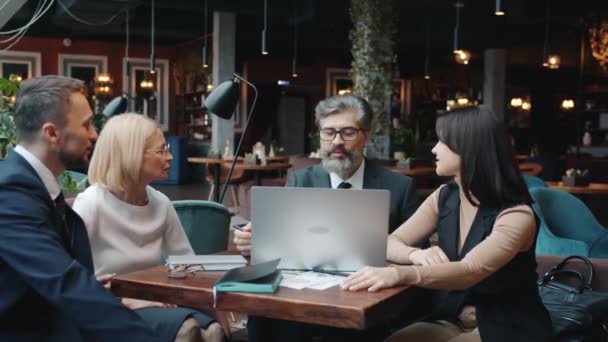 Bir grup işadamı ve kadın ve erkek, laptopla yapılan görüşmeler sırasında kafede konuşuyor. — Stok video